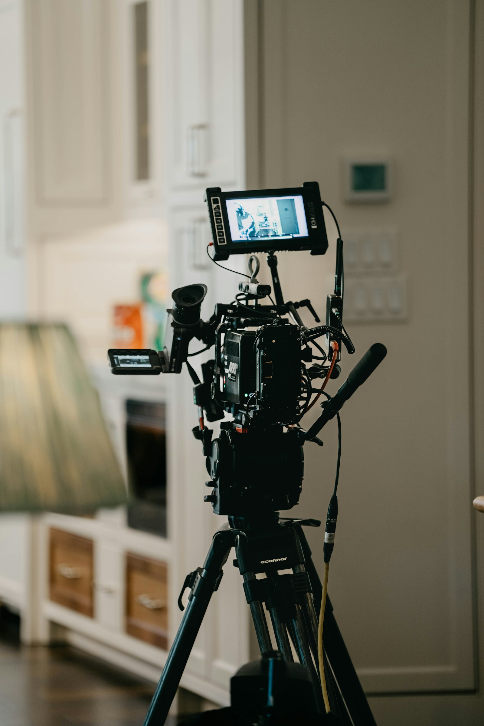 A professional cinema camera on a tripod inside a modern residential interior, framed up to capture vacation rental listing photography