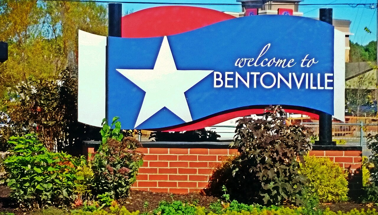 Welcome to Bentonville sign with a white star on blue, the greeting that meets Walmart transferees relocating to Northwest Arkansas
